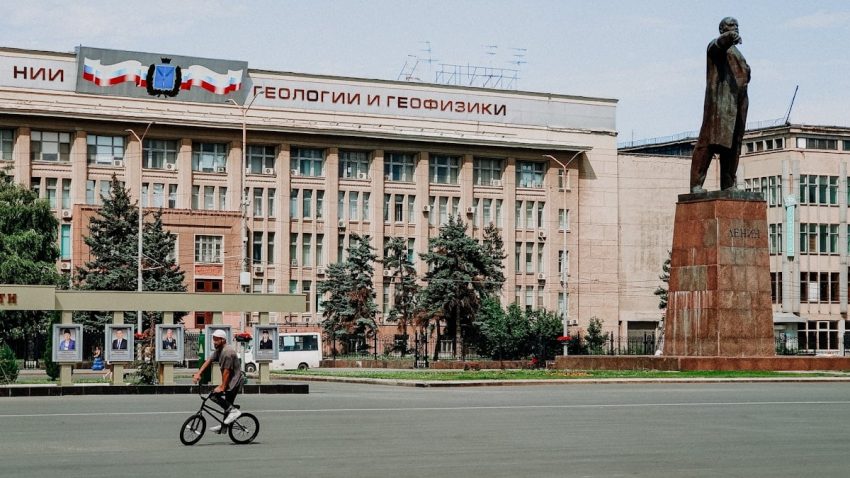 man riding bicycle in front of brown concrete building during daytime